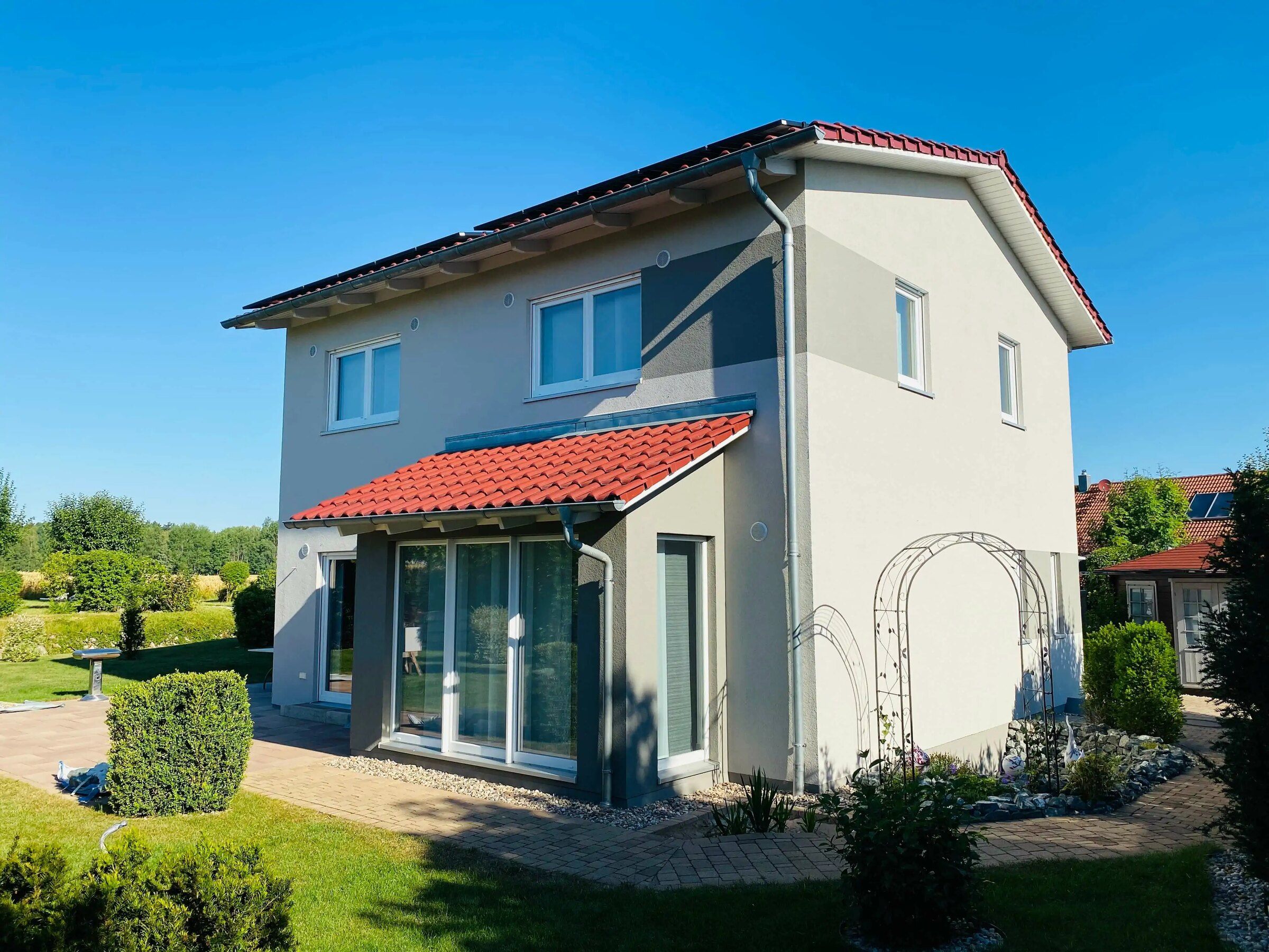 Frisch gestrichenes Einfamilienhaus mit weißer Fassade und roten Dachziegeln
