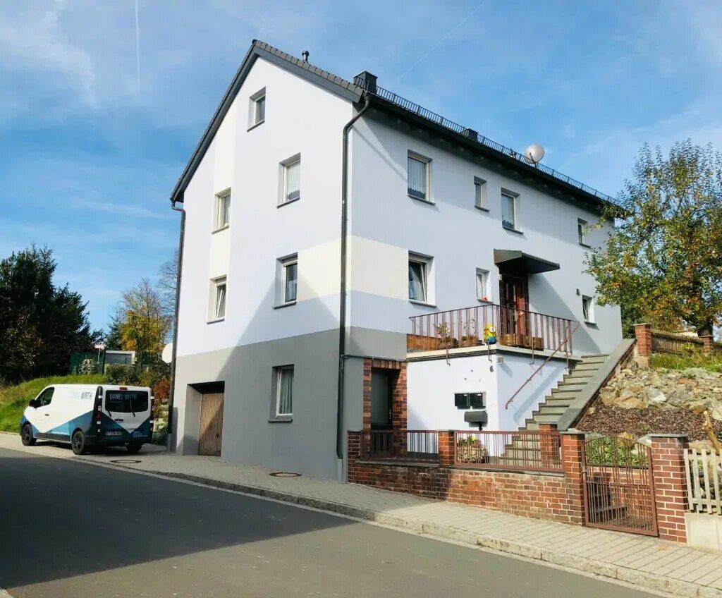 Weiße Fassade, davor der Firmenwagen