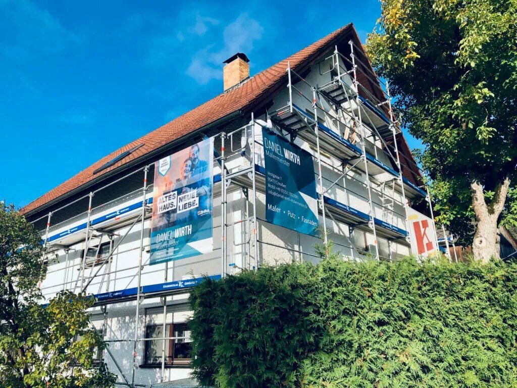 Eingerüstetes Wohnhaus mit Firmenplane